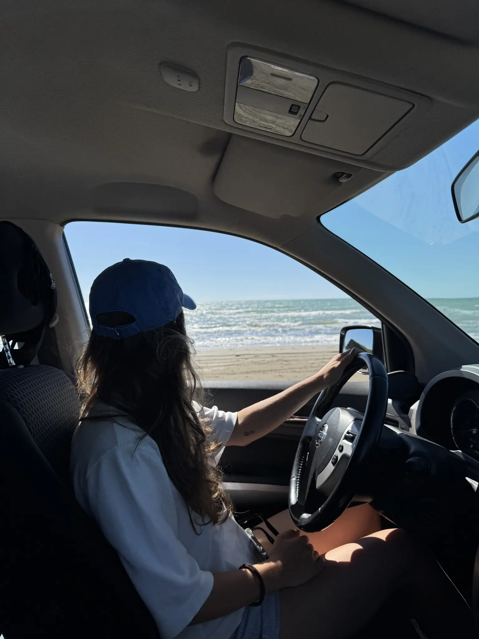 person driving car on beach looking at the sea