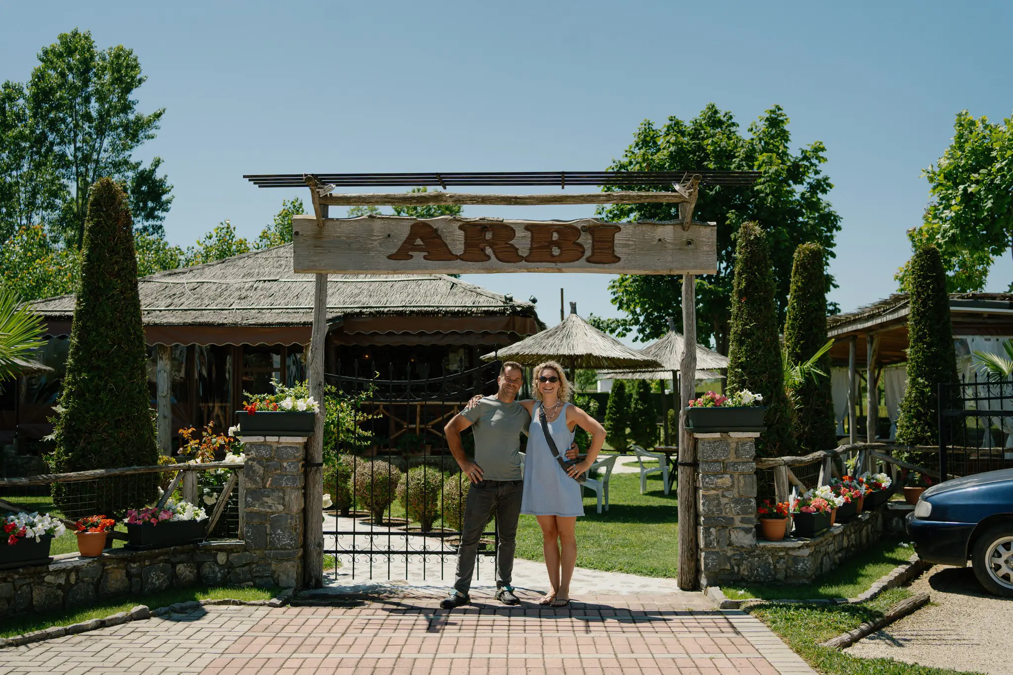 couple posing under Arbi sign at restaurant entrance