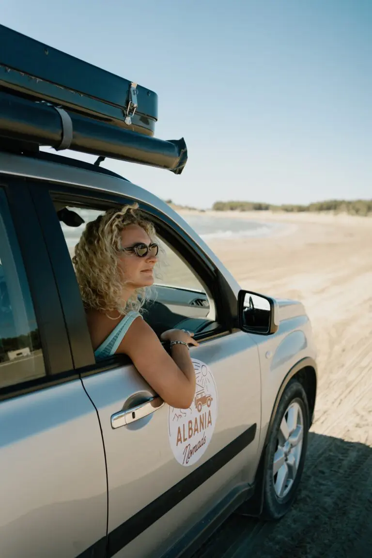 woman in car looking out window on sandy beach