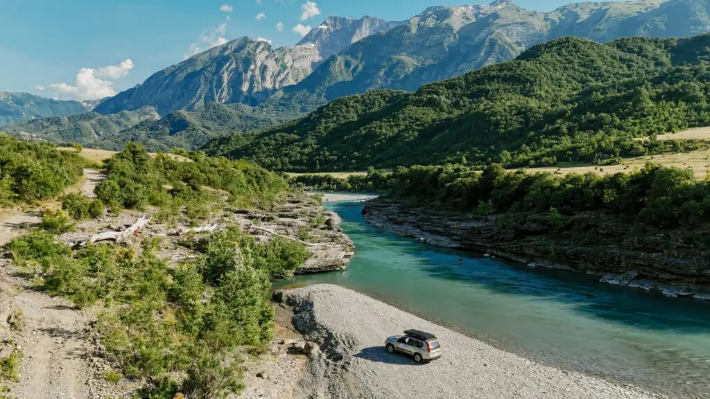 drone shot of a car parked by a turquoise river in Albania