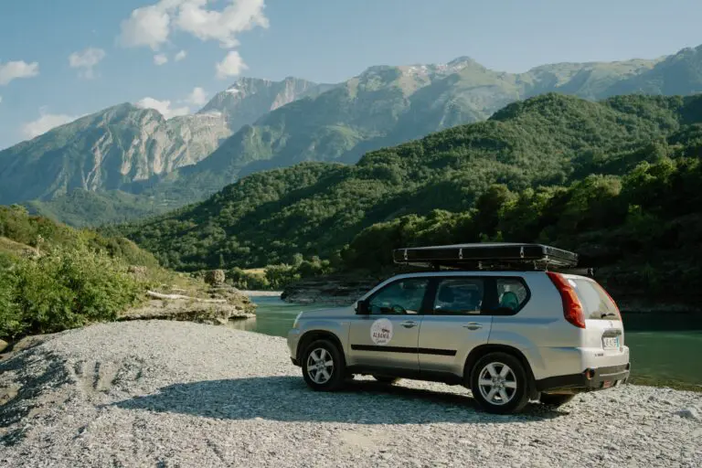 silver SUV with roof tent parked by a river in Albania