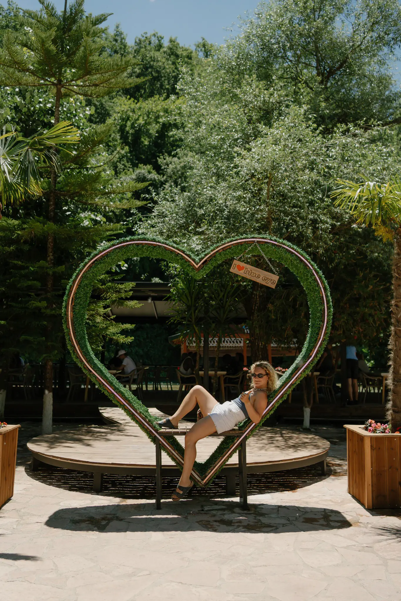 woman relaxing in heart-shaped archway at outdoor cafe
