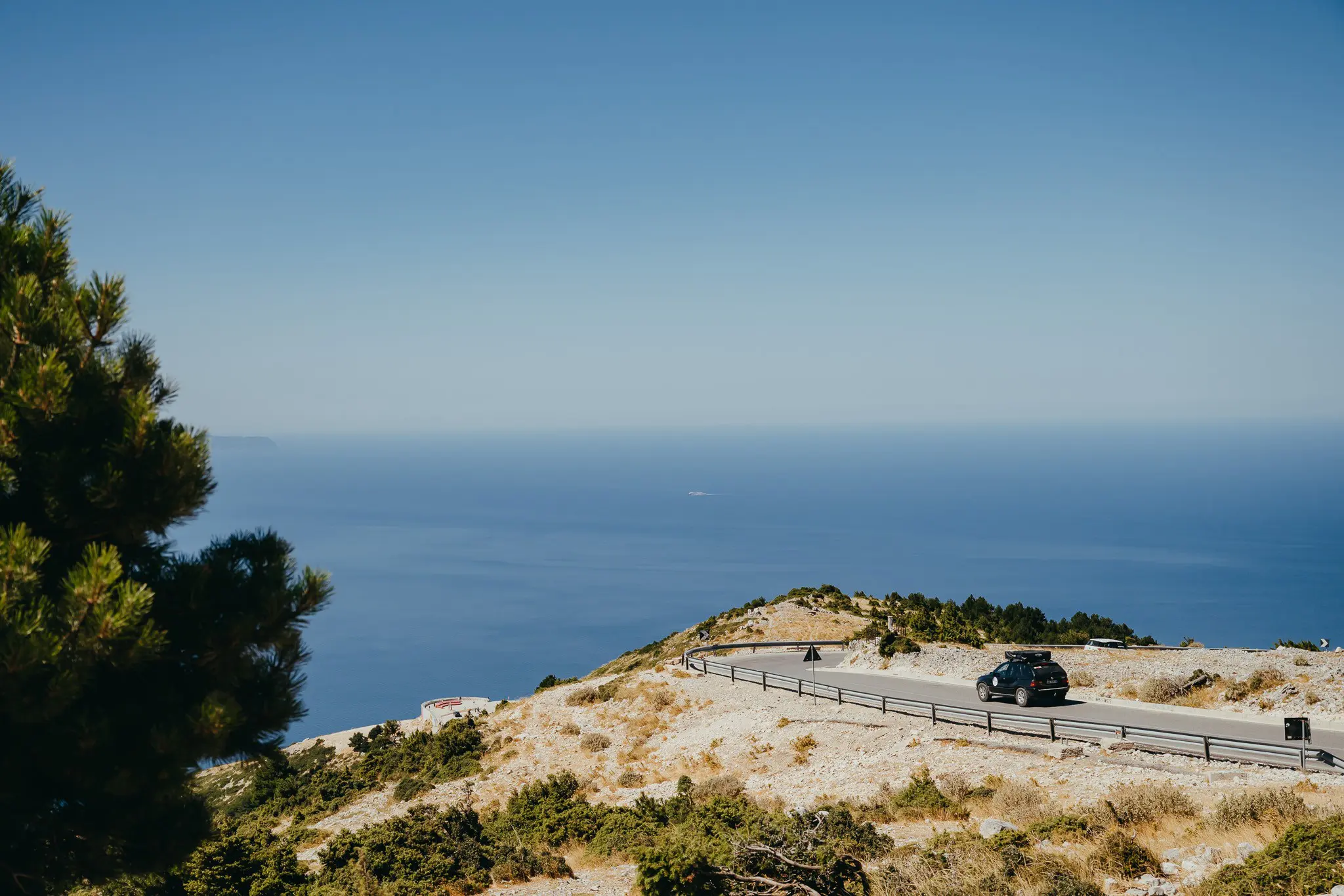 car driving on winding coastal road in Albania