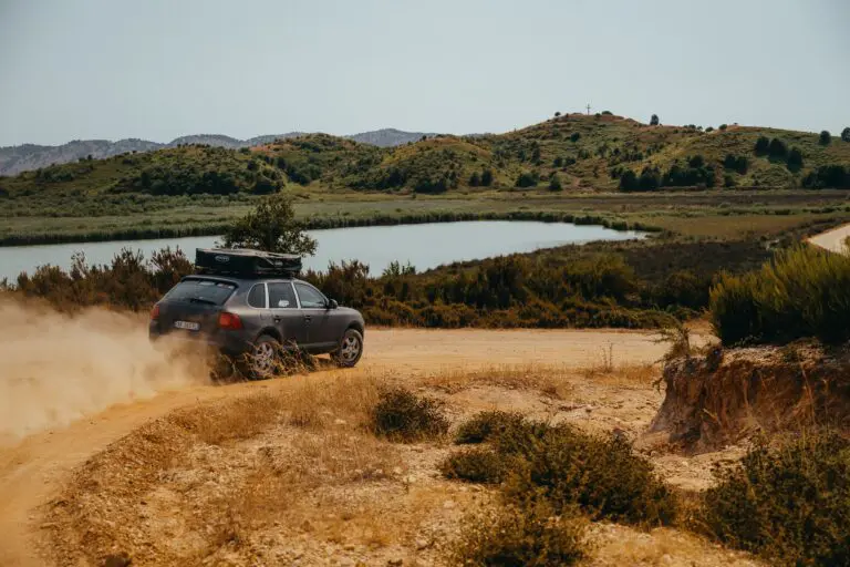 car driving on a dusty road next to a lake in Albania