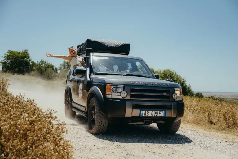 woman leaning out of Land Rover window on dusty road