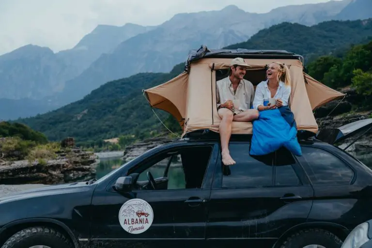 couple enjoying coffee in rooftop tent on car in Albania